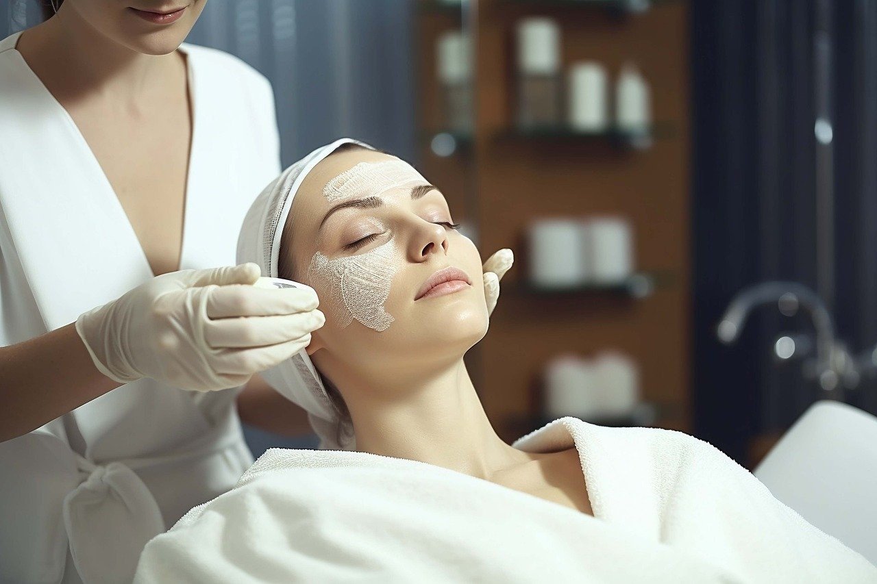 zrelaksowana klientka salonu kosmetycznego w trakcie zabiegu na twarz wykonywanego przez specjalistkę